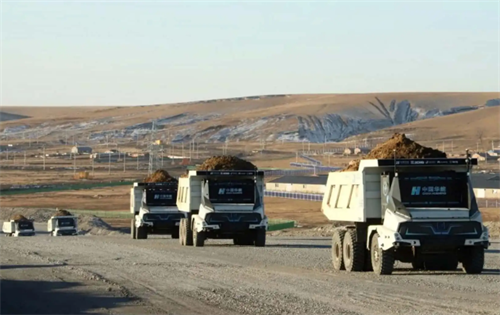 A fleet of autonomous mining trucks working in an open-pit mine, illustrating how industrial autonomy has already achieved operational efficiency and profitability.